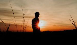 Preview wallpaper silhouette, man, light, sunset, sky, grass