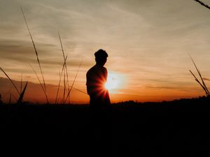 Preview wallpaper silhouette, man, light, sunset, sky, grass