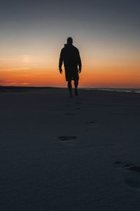 Preview wallpaper silhouette, sand, footprints, beach, sea, sunset, twilight