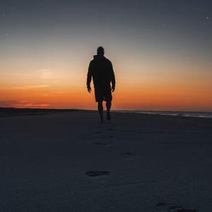 Preview wallpaper silhouette, sand, footprints, beach, sea, sunset, twilight