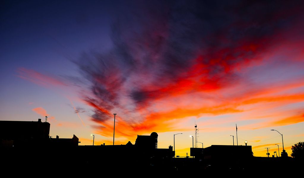 1024x600 Wallpaper silhouettes, city, buildings, clouds, colorful, sunset, sky, dark