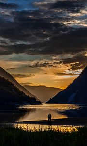 Preview wallpaper silhouettes, couple, mountains, lake, sunset, clouds, norway