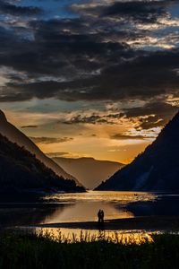 Preview wallpaper silhouettes, couple, mountains, lake, sunset, clouds, norway