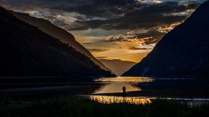 Preview wallpaper silhouettes, couple, mountains, lake, sunset, clouds, norway