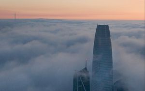 Preview wallpaper skyscraper, building, clouds, fog, city