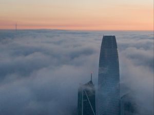 Preview wallpaper skyscraper, building, clouds, fog, city