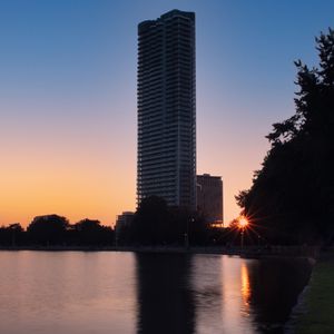 Preview wallpaper skyscraper, building, pond, sunset, city