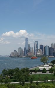 Preview wallpaper skyscraper, buildings, city, trees, bushes, clouds, sky