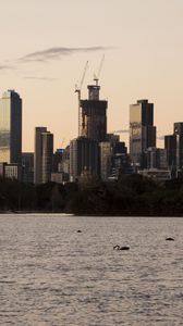 Preview wallpaper skyscrapers, buildings, trees, river, sunrise, city