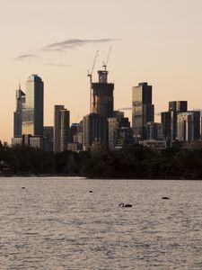 Preview wallpaper skyscrapers, buildings, trees, river, sunrise, city