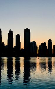 Preview wallpaper skyscrapers, city, buildings, water, silhouette, glare