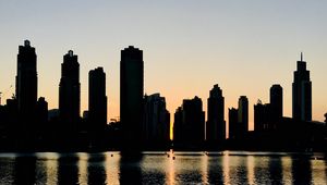 Preview wallpaper skyscrapers, city, buildings, water, silhouette, glare