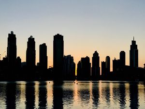 Preview wallpaper skyscrapers, city, buildings, water, silhouette, glare