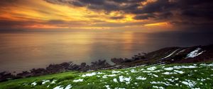 Preview wallpaper snow, grass, green, coast, sea, clouds, sky, orange, decline, anomaly