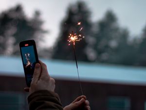 Preview wallpaper sparkler, hand, phone, sparks