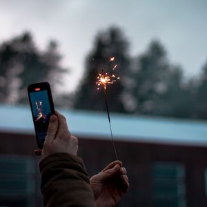 Preview wallpaper sparkler, hand, phone, sparks