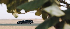 Preview wallpaper sports car, car, sand, branches, leaves