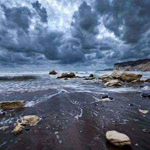 Preview wallpaper stones, foam, sea, clouds, sky, gloomy, sand, wet, cloudy