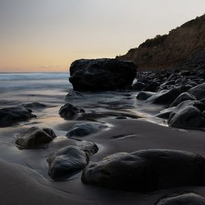 Preview wallpaper stones, sand, water, wet, coast, sea, twilight