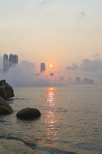 Preview wallpaper stones, sea, fog, city, sunrise