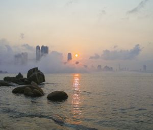 Preview wallpaper stones, sea, fog, city, sunrise