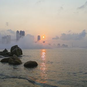 Preview wallpaper stones, sea, fog, city, sunrise