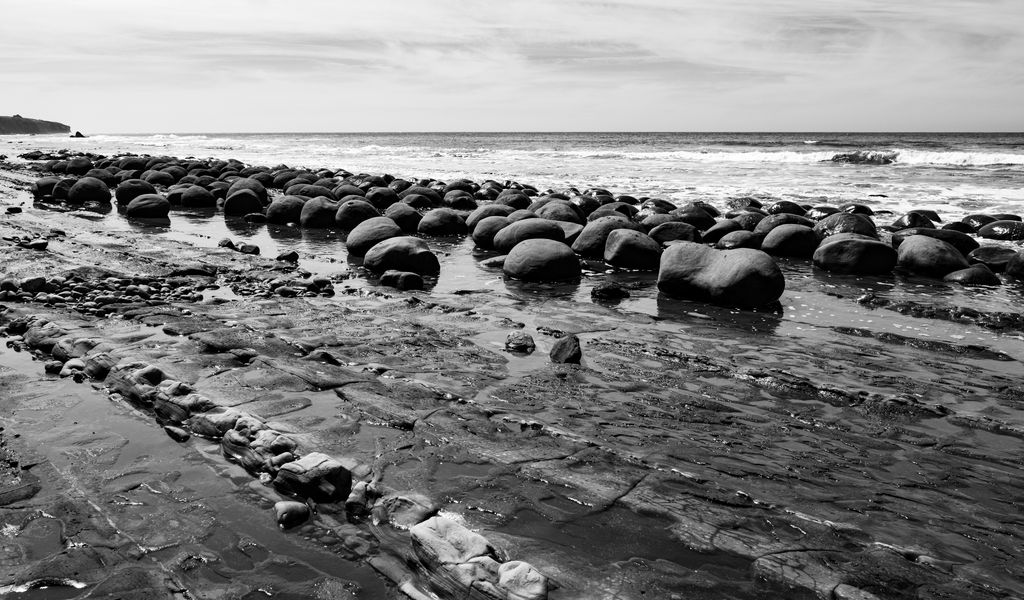 1024x600 Wallpaper stones, sea, water, beach, horizon, bw