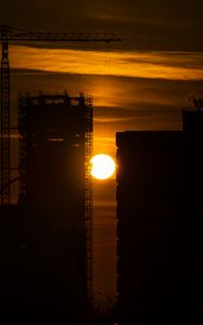 Preview wallpaper sun, buildings, outlines, sunset, dark, building, crane