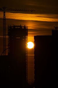 Preview wallpaper sun, buildings, outlines, sunset, dark, building, crane