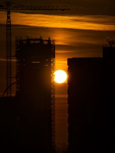 Preview wallpaper sun, buildings, outlines, sunset, dark, building, crane