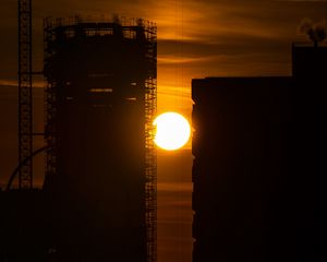 Preview wallpaper sun, buildings, outlines, sunset, dark, building, crane