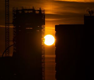 Preview wallpaper sun, buildings, outlines, sunset, dark, building, crane