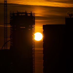 Preview wallpaper sun, buildings, outlines, sunset, dark, building, crane