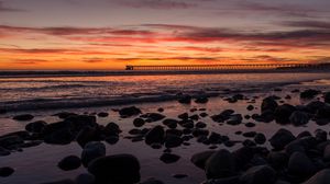 Preview wallpaper sunset, bridge, sea, stones, horizon