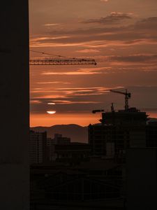 Preview wallpaper sunset, buildings, silhouettes, sun, clouds, dark