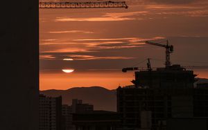 Preview wallpaper sunset, buildings, silhouettes, sun, clouds, dark