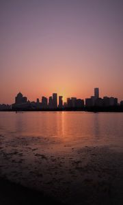 Preview wallpaper sunset, city, building, rays, sea