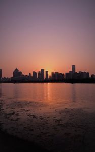 Preview wallpaper sunset, city, building, rays, sea