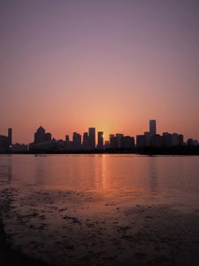 Preview wallpaper sunset, city, building, rays, sea