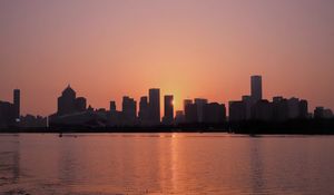 Preview wallpaper sunset, city, building, rays, sea