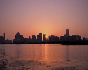 Preview wallpaper sunset, city, building, rays, sea