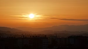 Preview wallpaper sunset, city, buildings, mountains, dusk