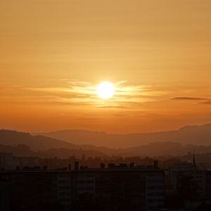 Preview wallpaper sunset, city, buildings, mountains, dusk