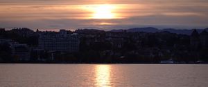 Preview wallpaper sunset, city, coast, buildings, water