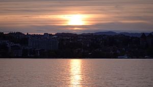 Preview wallpaper sunset, city, coast, buildings, water