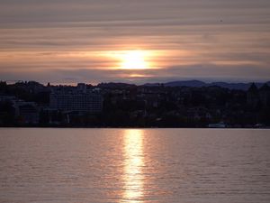 Preview wallpaper sunset, city, coast, buildings, water
