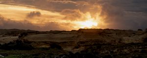 Preview wallpaper sunset, clouds, stones, sand, nature