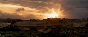 Preview wallpaper sunset, clouds, stones, sand, nature