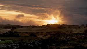 Preview wallpaper sunset, clouds, stones, sand, nature