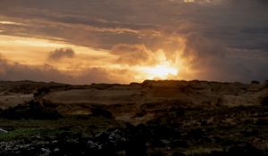 Preview wallpaper sunset, clouds, stones, sand, nature